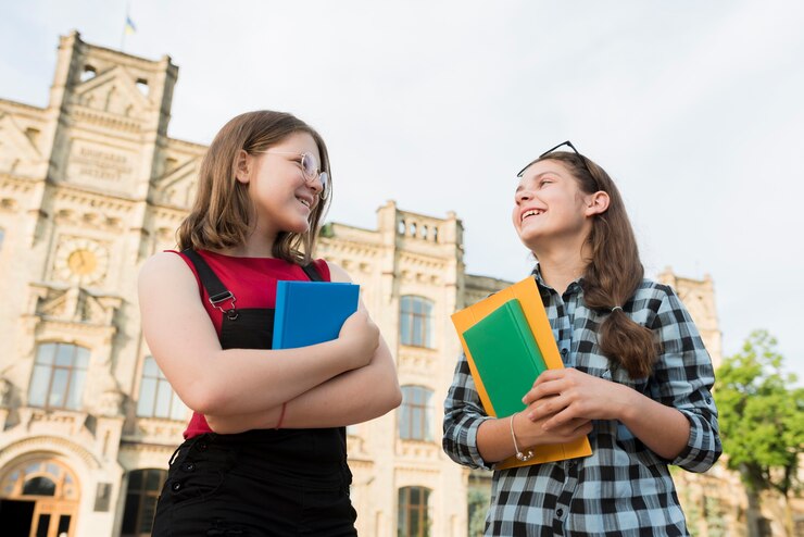 Two MBA girl students holding study materials in hand and and talking